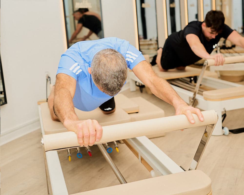 A member stretching forward over the footbar of a reformer